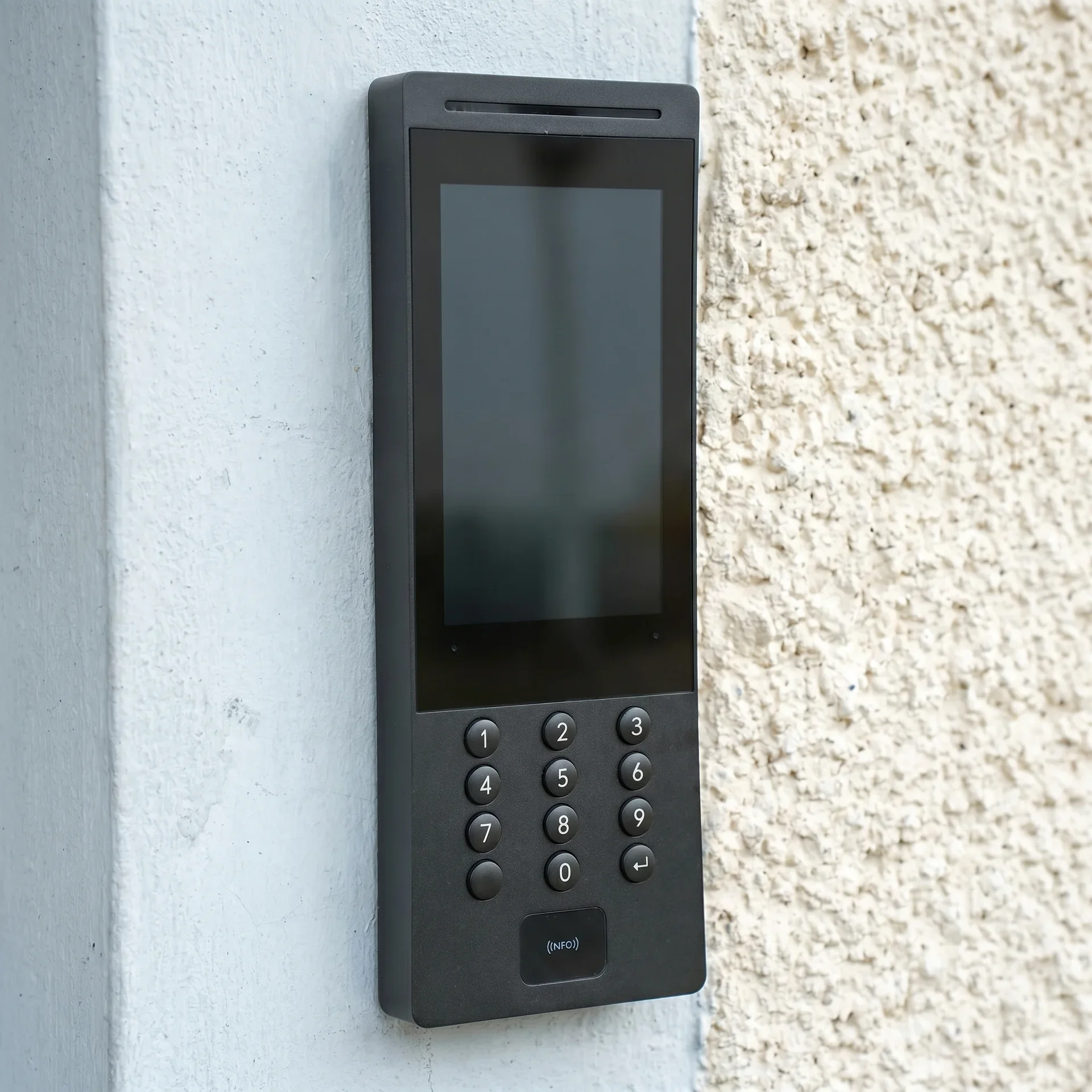 Modern porttelefon med knappsats och skärm monterad på vägg.
