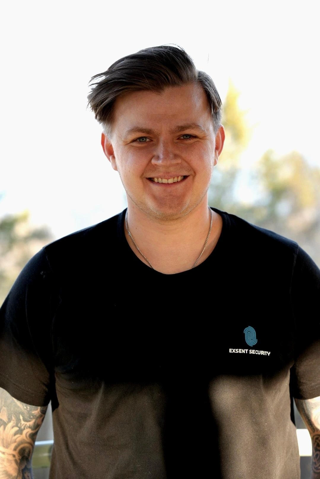 En leende man i svart t-shirt med Exsent Security-logga