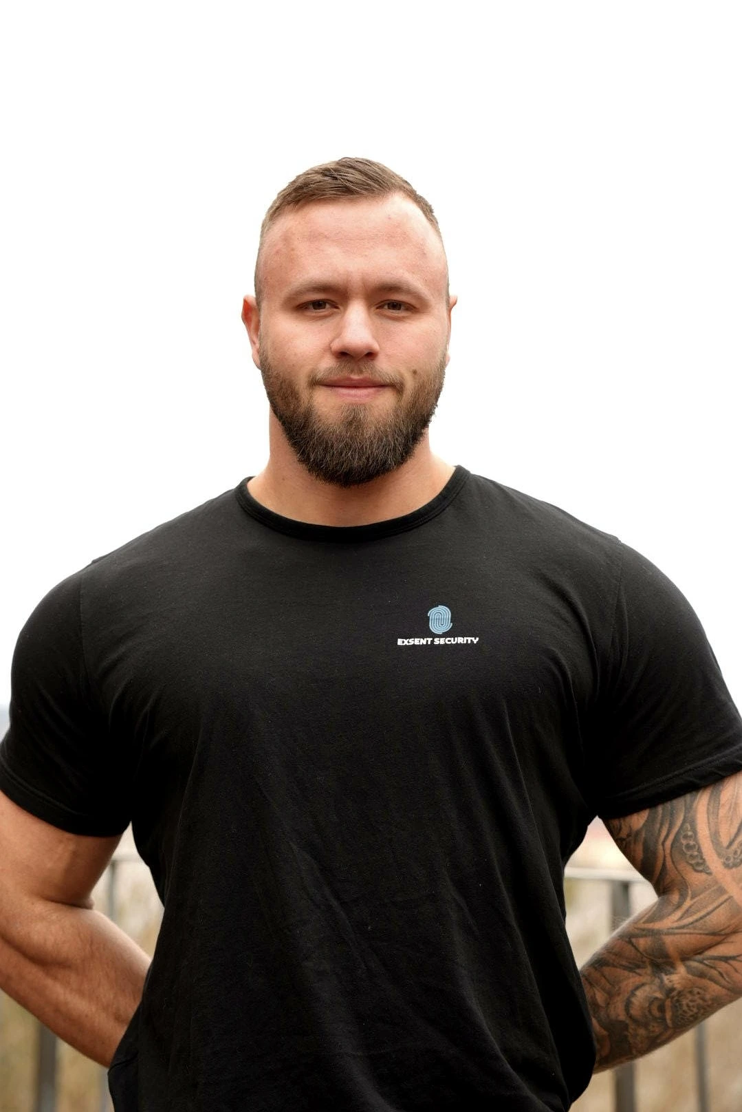 Man i svart t-shirt med Exsent Security-logotyp mot vit bakgrund.